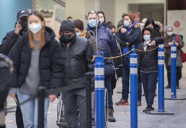 Masked people wait in line at vaccination clinic