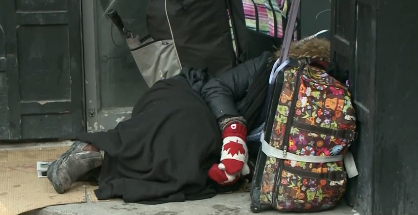 homeless person lying down, wearing gloves, face hidden