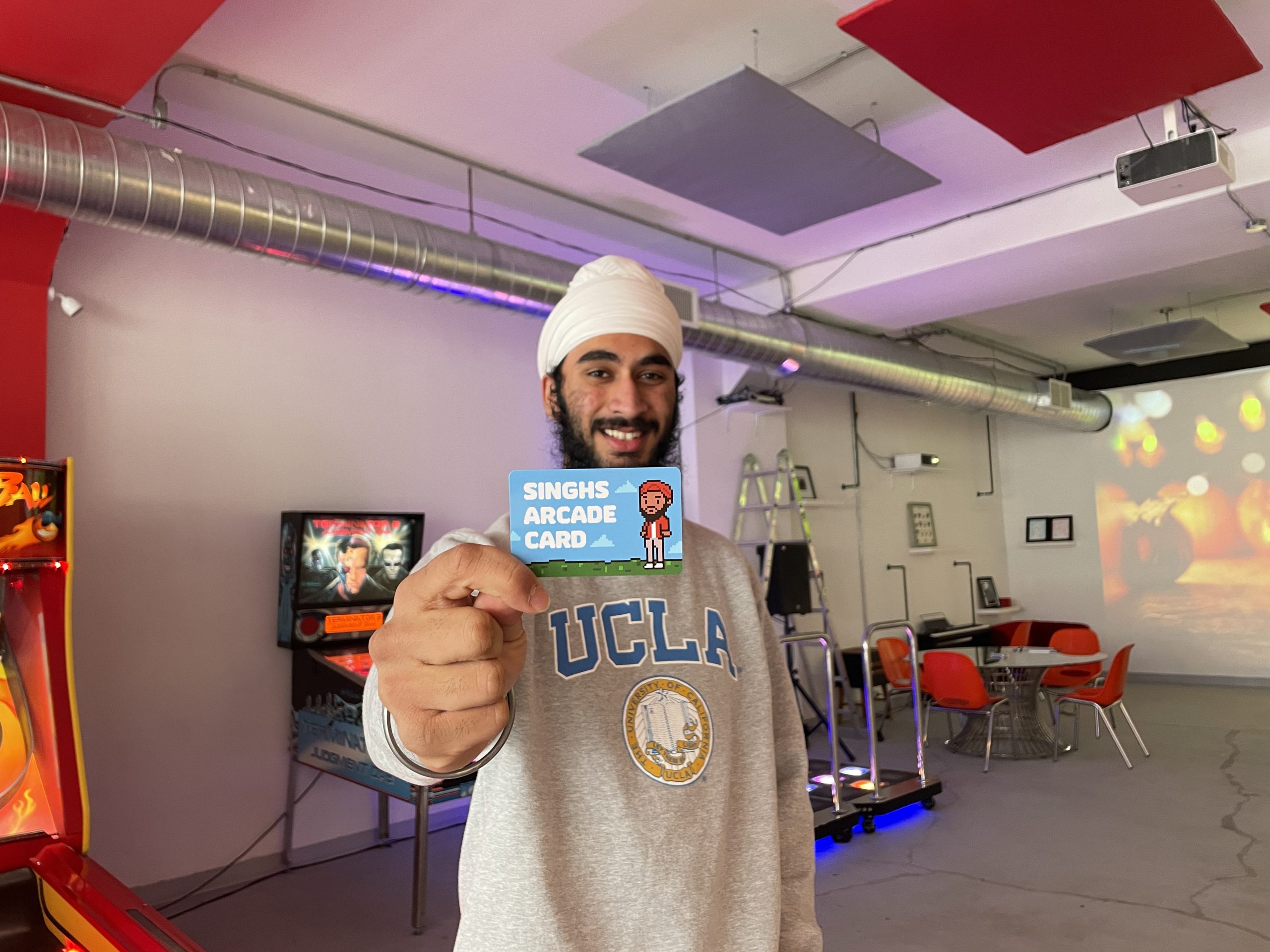 Gursagar Singh holding up a play pass to his arcade 