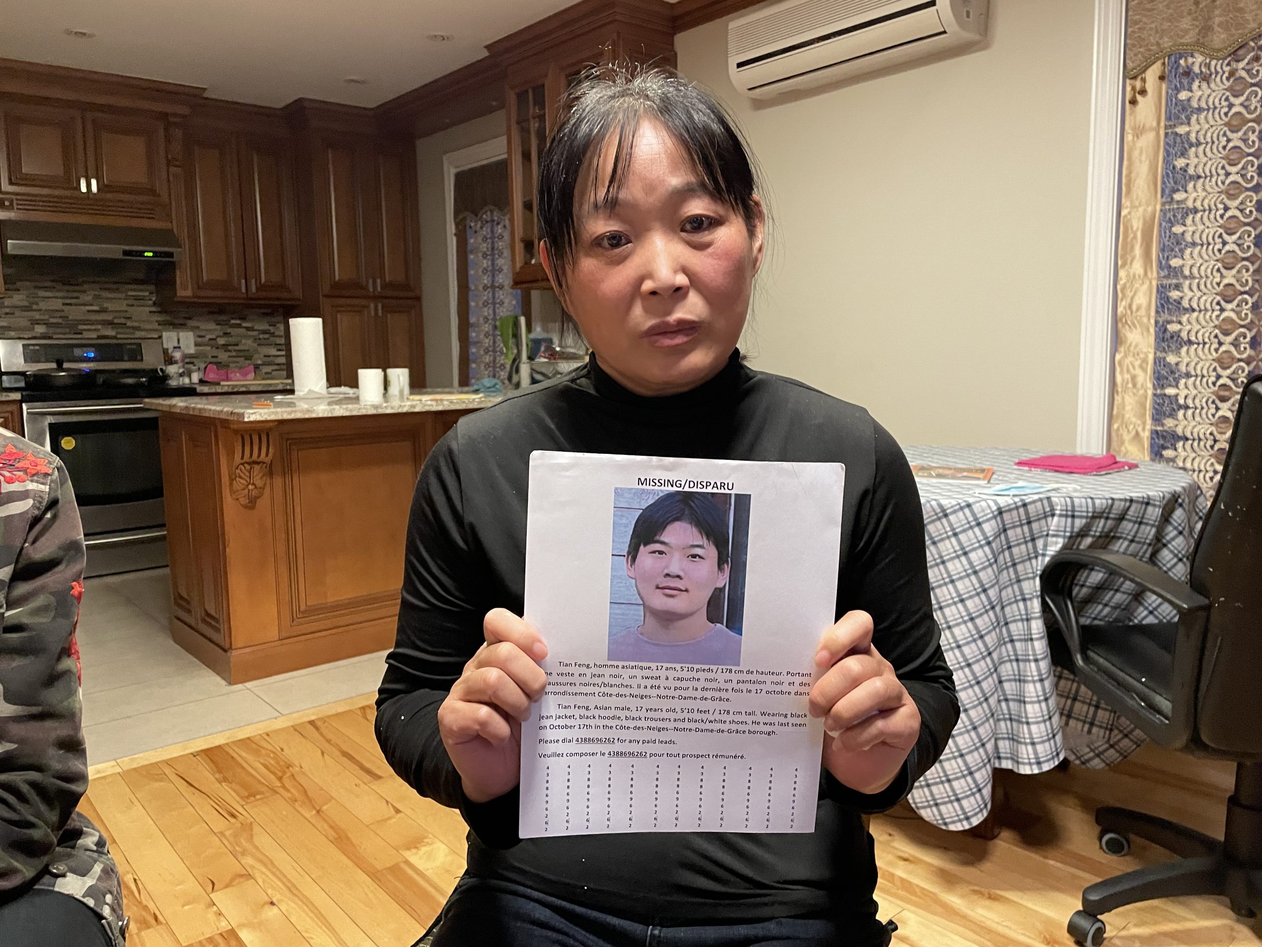 La madre de Feng Tian, ​​Sujing Nie, sostiene un volante perdido de su hijo, que ha estado desaparecido desde el 17 de octubre.