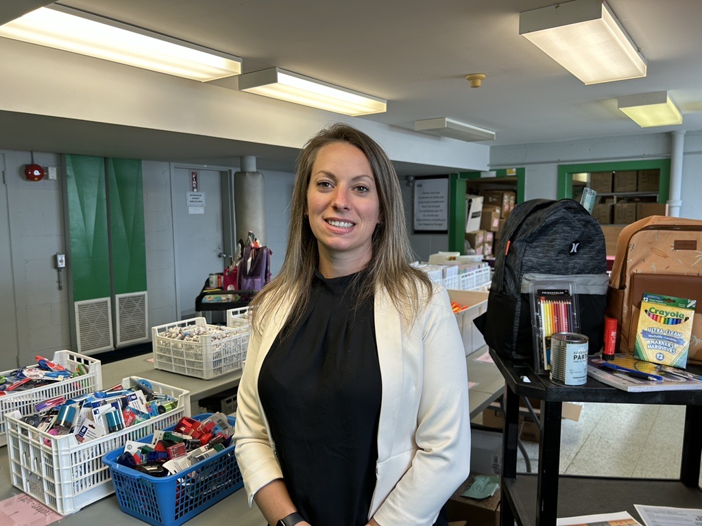 Audrey Renaud, the general manager of Regroupement Partage standing infront of some supplies that are part of their back to school program