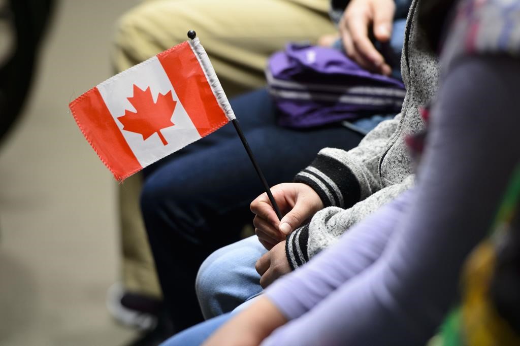 A person is seen holding a flag in their hands as they sit down on April 17, 2019. THE CANADIAN PRESS/Sean Kilpatrick