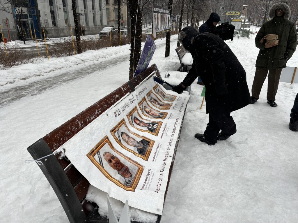 A person is seen leaning over a bench with a picture with peoples faces on it