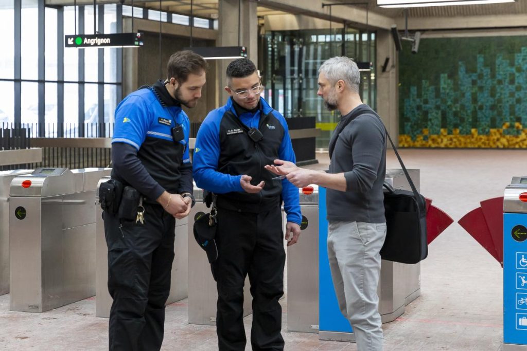 Dos embajadores de la seguridad ayudan a un cliente en el metro de Place-des-Arts