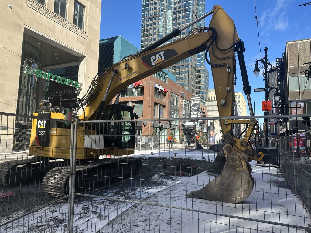 A large excavator digs on Saint-Catherine Street