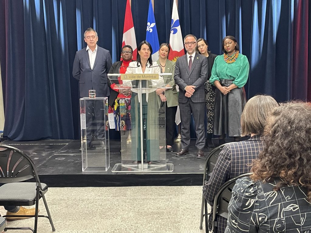 Montreal Mayor Valérie Plante is seen on stage at a press conference with several other people