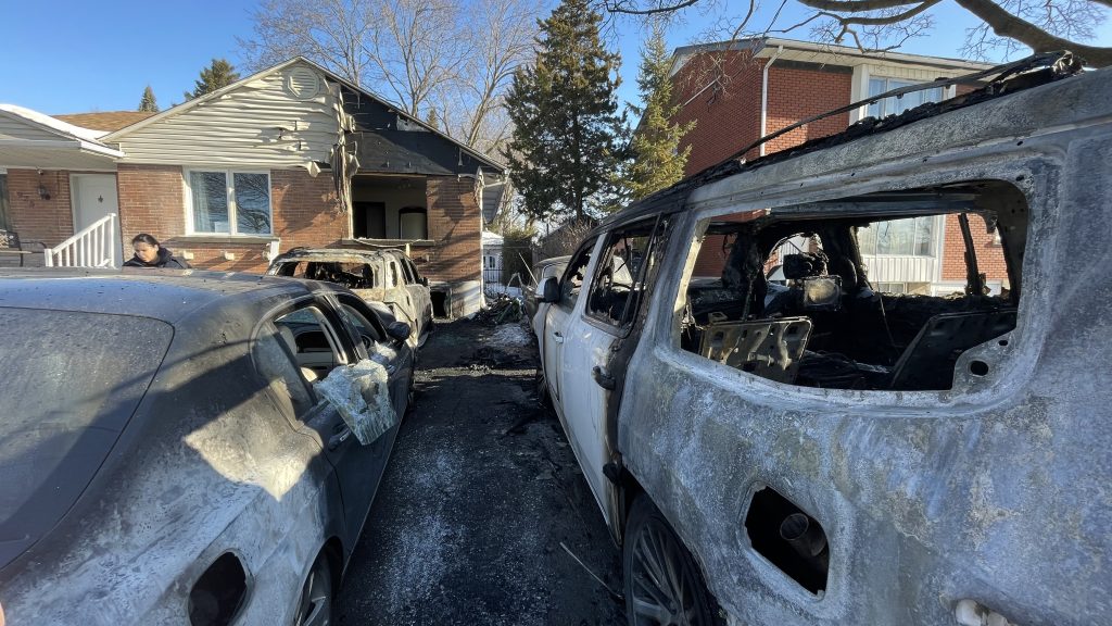 The front of a house along with three cars are seen with fire damage in Saint-Laurent