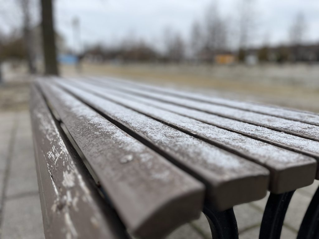 A park bench is seen covered in snow