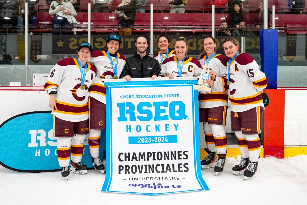 El equipo de hockey femenino de Concordia posa con una pancarta del campeonato