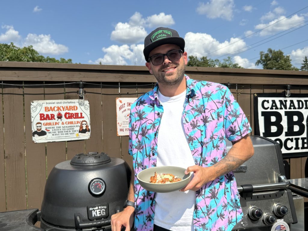 A man dressed in a purple and blue shirt is smiling while holding a plate of food,