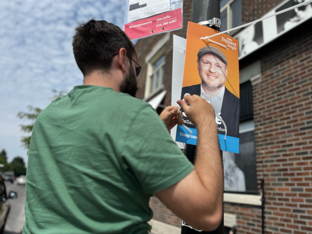 A volunteer hangs a poster Craig Sauvé