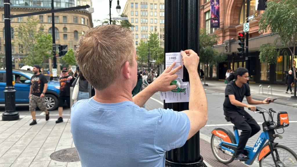 Wayne Adam puts up poster on street pole